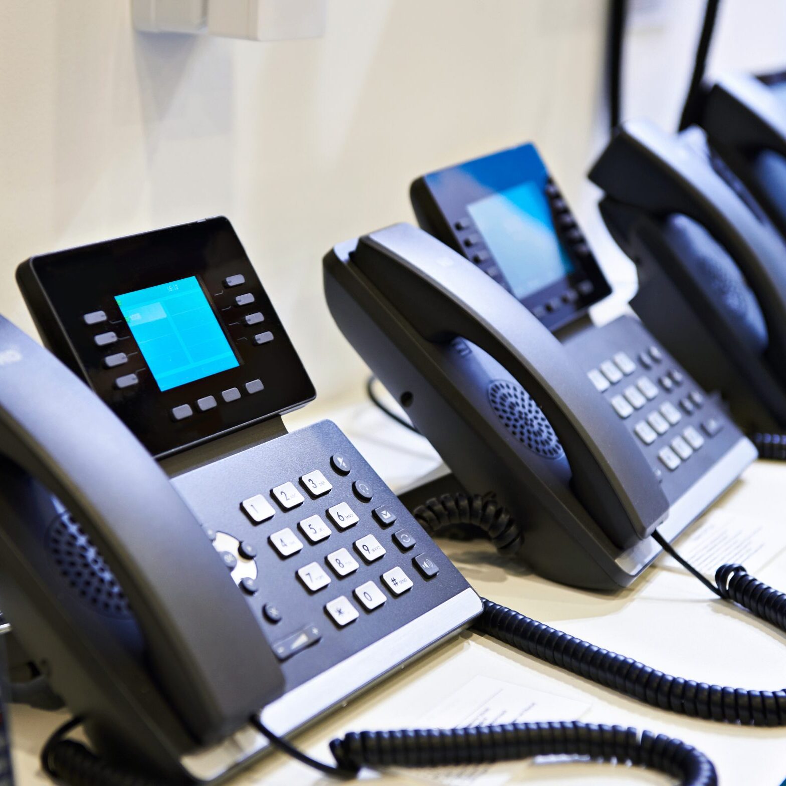 Office desk phones lined up in a row.